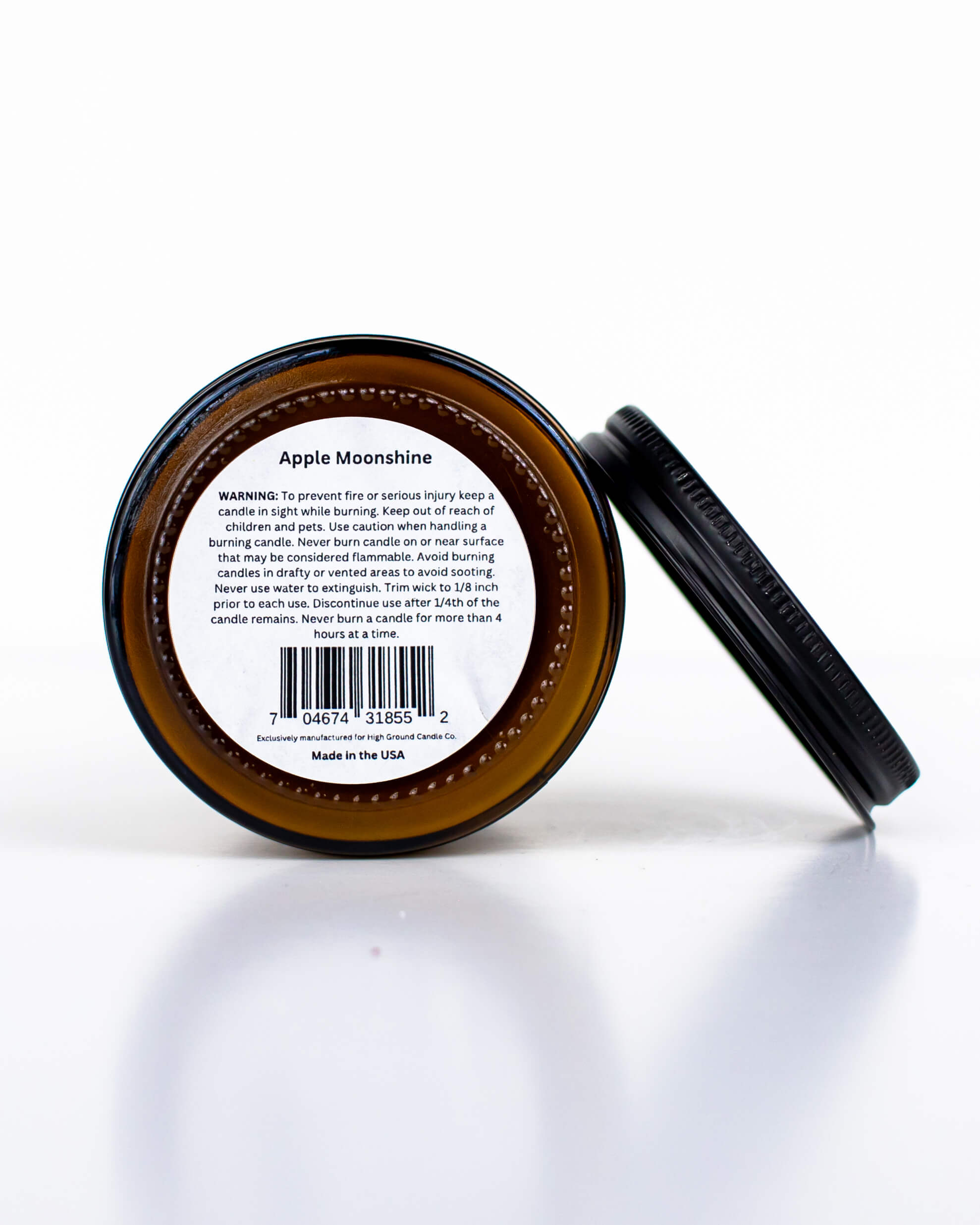 Buff Bar All-natural candle in a amber glass with black lid and warning label featuring the Apple Moonshine fragrance. The candle is on a white background.