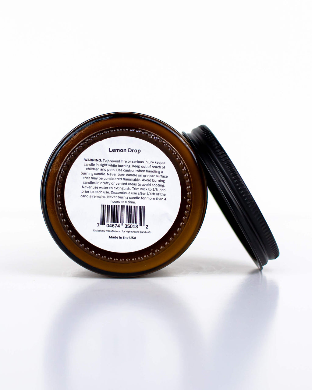 Buff Bar All-natural candle in a amber glass with black lid and warning label featuring the Lemon Drop fragrance. The candle is on a white background.