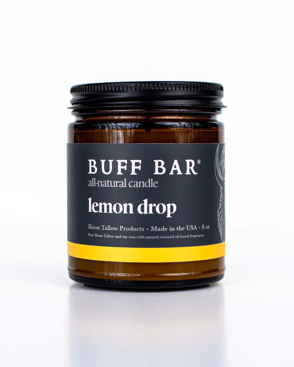 Buff Bar All-natural candle in a amber glass with black lid and label featuring the Lemon Drop fragrance and the Buff Bar Bison illustration. The candle is on a white background.