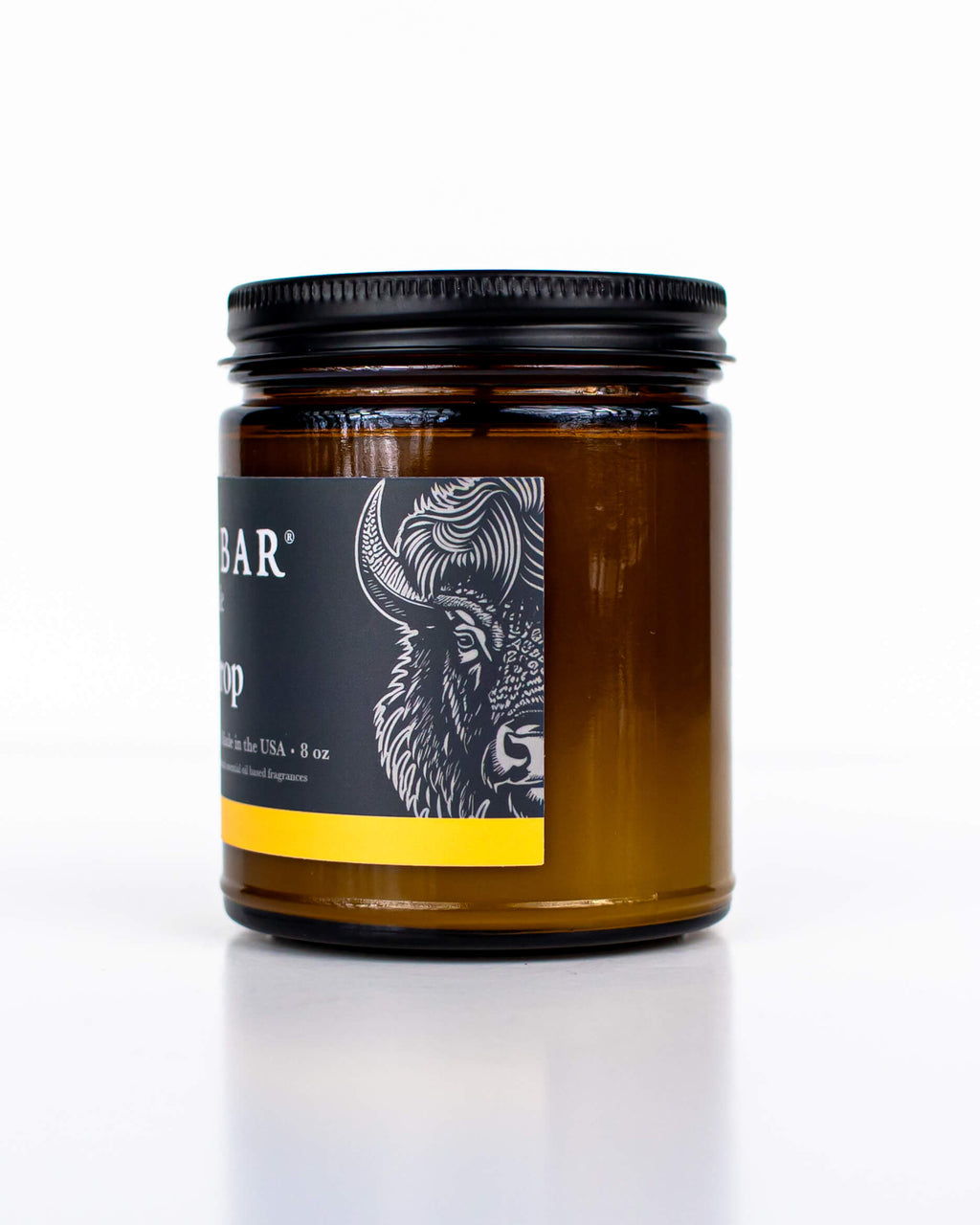 Buff Bar All-natural candle in a amber glass with black lid and label featuring the Lemon Drop fragrance and the Buff Bar Bison illustration. The candle is on a white background.