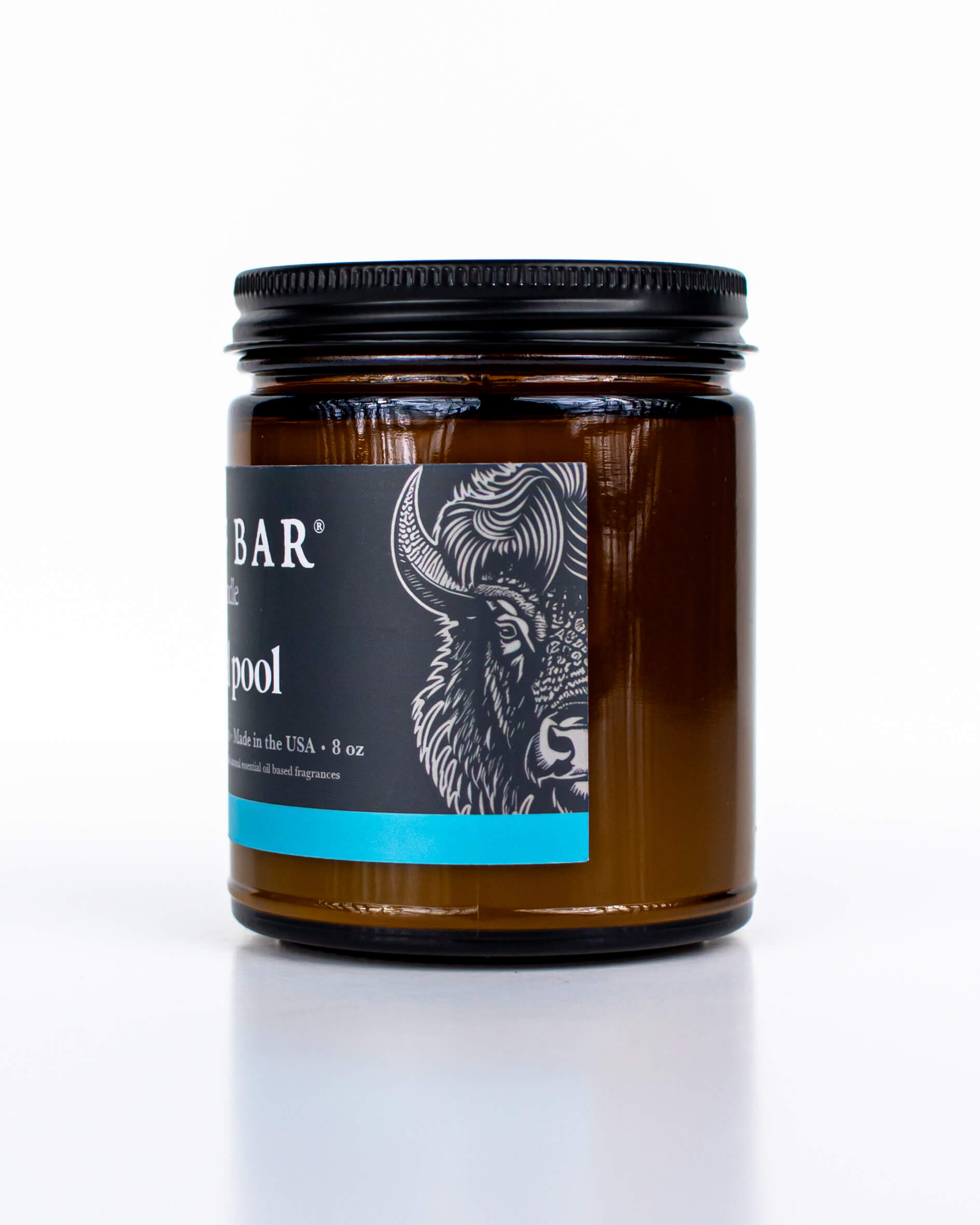 Buff Bar All-natural candle in a amber glass with black lid and label featuring the Mineral Pool fragrance and the Buff Bar Bison illustration. The candle is on a white background.
