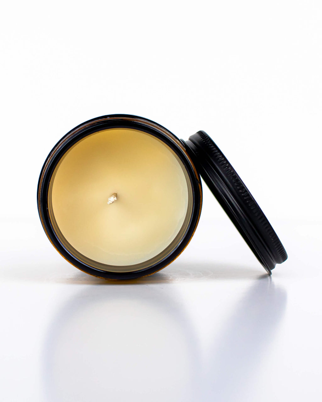 All-Natural Bison Tallow Candle in a glass jar with a black lid on a white background.