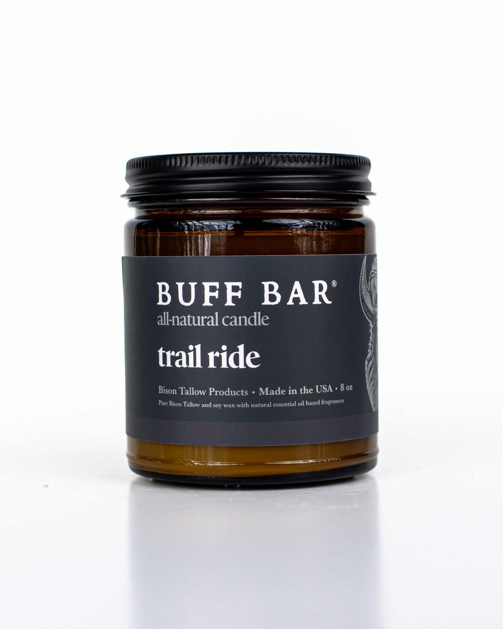 Buff Bar All-natural candle in a amber glass with black lid and label featuring the Trail Ride fragrance and the Buff Bar Bison illustration. The candle is on a white background.