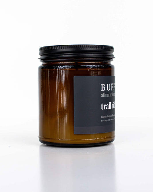 Buff Bar All-natural candle in a amber glass with black lid and label featuring the Trail Ride fragrance and the Buff Bar Bison illustration. The candle is on a white background.